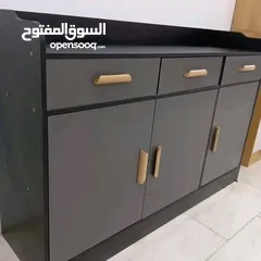  3 خزانة بتصميم راقٍ يجمع بين العملية والجمال، بلون رمادي أنيق ولمسات سوداء، مع مقابض ذهبية تضيف فخام