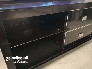  9 طاولة تلفزيون لون اسون بحالة ممتازة للبيع درجين وسطانيات واماكن تخزين جانبية  سطح زجاجي وارفف زجاجية