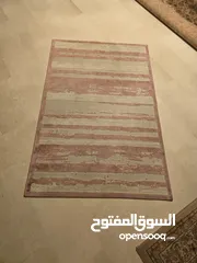  2 سجادة بلون الزهري و ابيض بجانب السرير