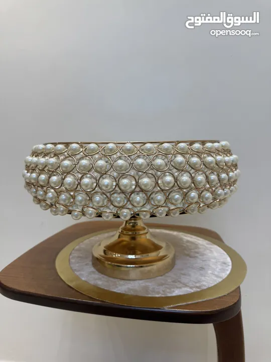 تحف منزليه باللون الذهبي على شكل دائري مزينه بالؤلؤ  ويمكن استخدامها للضيافه او تزيينها بالورود