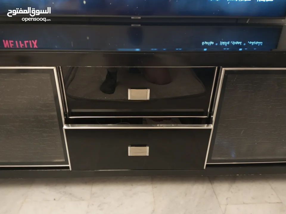 طاولة تلفزيون لون اسون بحالة ممتازة للبيع درجين وسطانيات واماكن تخزين جانبية  سطح زجاجي وارفف زجاجية