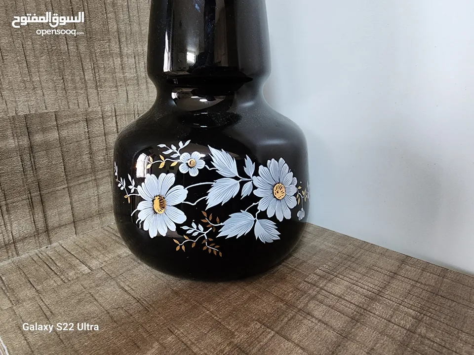 فازة مزهرية سوداء مزخرفة باللون الذهبي مع باقة ورد