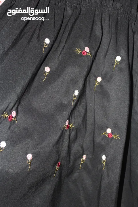 فستان نسائي قصير بقصة واسعة على الخصر، بلون أسود سادة، ومطرز بالورود