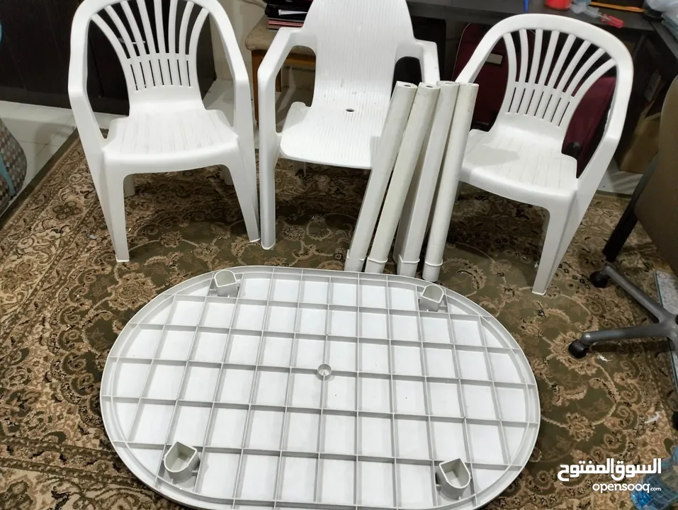 طاولة بلاستيك مع ثلاثة كراسي ومظلة