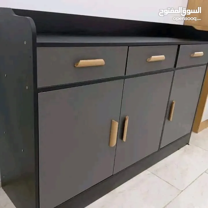 خزانة بتصميم راقٍ يجمع بين العملية والجمال، بلون رمادي أنيق ولمسات سوداء، مع مقابض ذهبية تضيف فخام