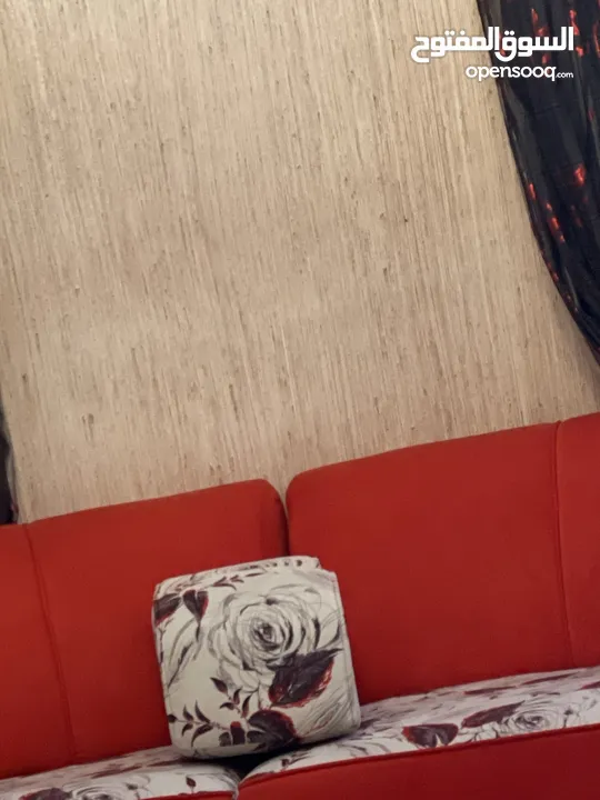 غرفة جلوس كبيره حمراء ويوجد معها كوشانات زياده ومساند تعتبر 18 مقعد ضهر باللون الاحمر والمقاعد معرقه