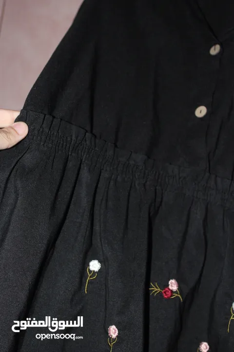 فستان نسائي قصير بقصة واسعة على الخصر، بلون أسود سادة، ومطرز بالورود