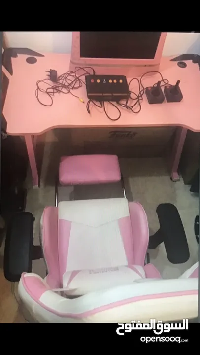 كرسي وطاولة وشاشة لون وردي وجهاز اتاري