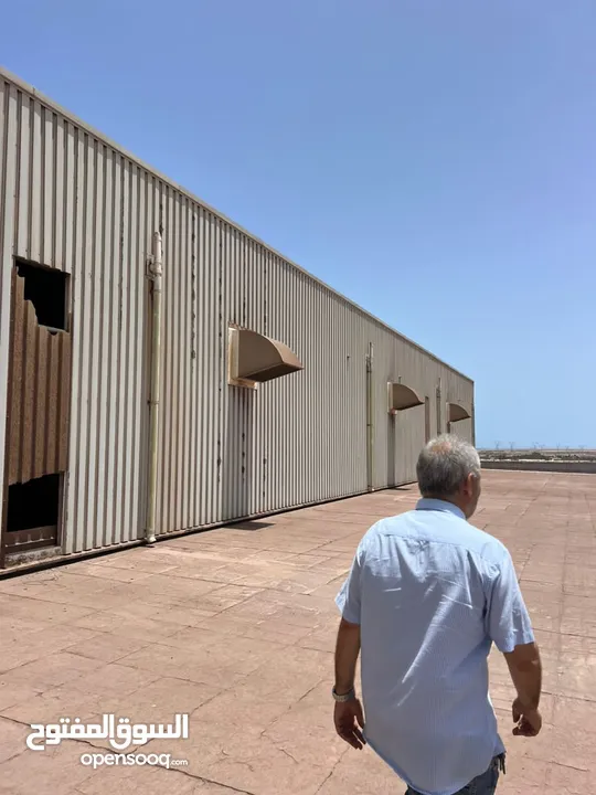 باستخدام الكاميرا  Workers are required to install corrugated sheets for a high-height hangar. The l