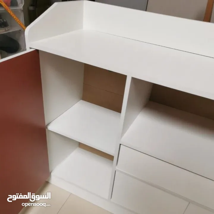 خزانة عملية مع مقابض خشبية بسيطة وأنيقة  تصميمها يجمع بين المساحات المغلقة والرفوف المفتوحة لسهولة