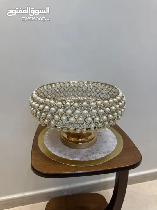 تحف منزليه باللون الذهبي على شكل دائري مزينه بالؤلؤ  ويمكن استخدامها للضيافه او تزيينها بالورود