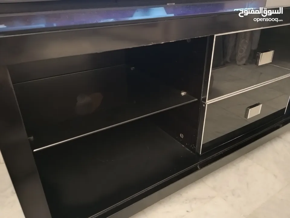 طاولة تلفزيون لون اسون بحالة ممتازة للبيع درجين وسطانيات واماكن تخزين جانبية  سطح زجاجي وارفف زجاجية