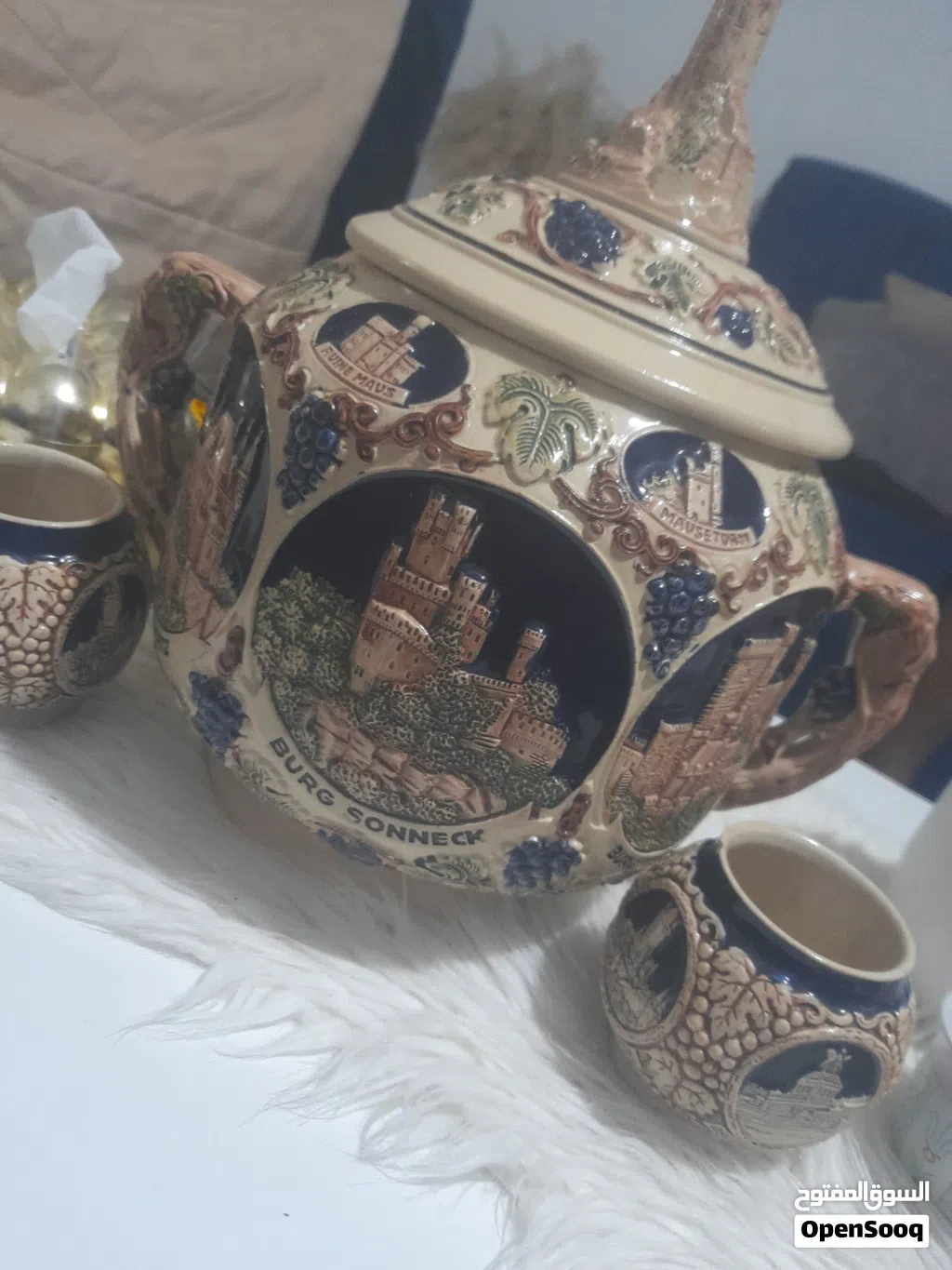 للبيع قطعة خزفية ألمانية قديمة مميزة مع غطاء وكأسين أصليين. تحمل رسومات بارزة لمعالم المانيه