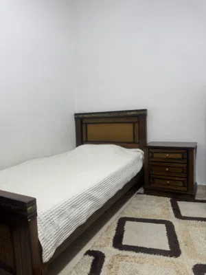 سرير خشب بني مستعمل مع طاولة سرير جانبية