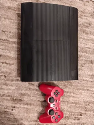 Sony PlayStation 3 Super Slim console along with a red Dualshock wireless controller.