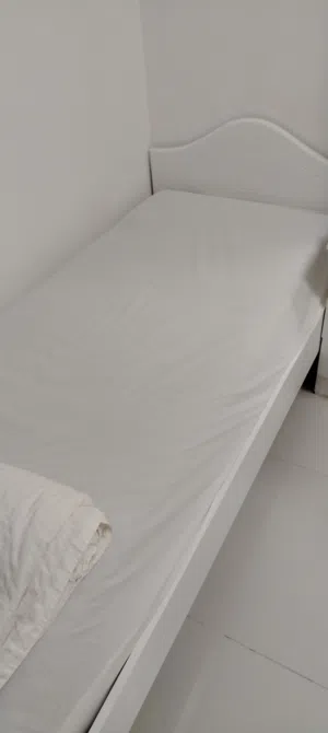 A single white wooden bed for one person.
