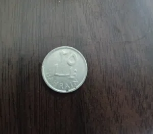 العملة في الصورة هي قطعة معدنية من فئة 25 فلس بحريني قديم عام 1965