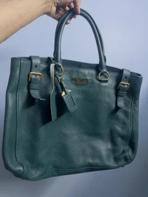 Prada Vitello Daino leather side-pocket tote bag in a teal or dark green color.