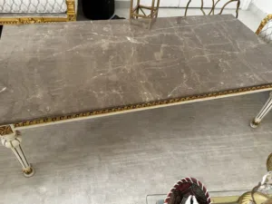 طاولة رخام فخمة وتتميز بسطح رخامي وإطار خشبي مزخرف باللون الذهبي.