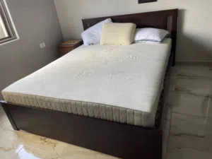 A king size bed with mattress and a side table