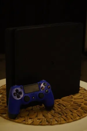 PlayStation 4 (slim) with a controller بليستيشن 4 (سليم) مستخدم مع جهاز