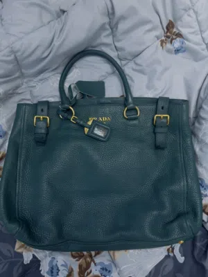 Prada Vitello Daino leather side-pocket tote bag in a teal or dark green color.