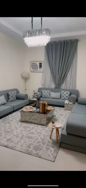 مجلس ارضي رمادي شامل الكنب والستارة والطاولات والنجفة