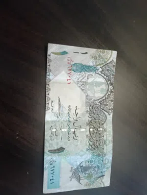 العملة الموضحة في الصورة هي الريال القطري، وتحديداً ورقة نقدية من فئة 1 ريال  (قديم إصدار الرابع )