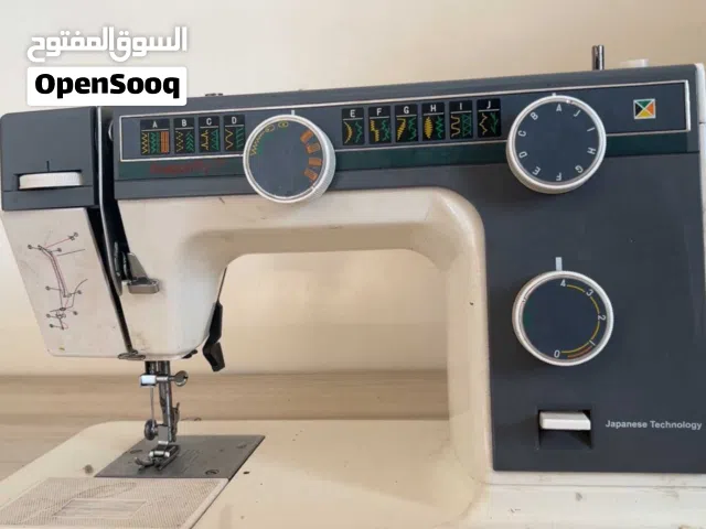 ماكينة خياطة جانومي طراز 393، وتتميز بهيكل معدني متين ولون أبيض مع تفاصيل رمادية./