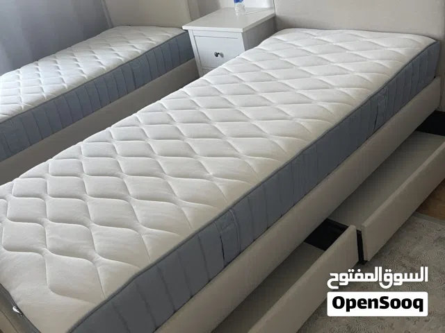 Two beds with mattress and bedside.