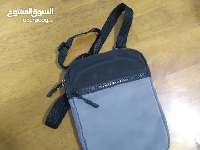 شنطة كتف صغيرة لون رمادي واسود.