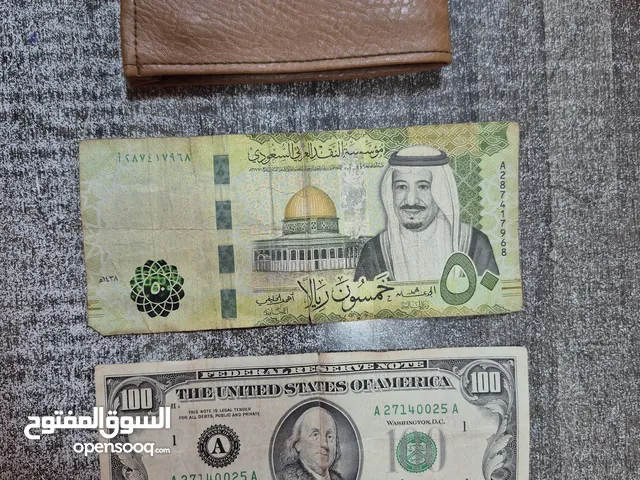 محفظة نقود من سنة 1980 و عملة فئة 100 دولار  أمريكي.   و عملة 50 ريال سعودي.