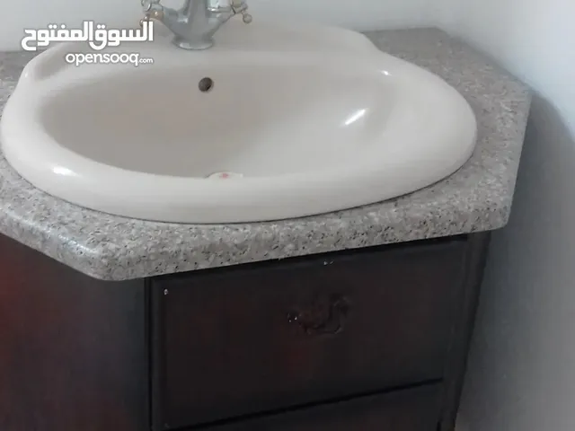 مغسلة مع حنفية وسطح رخام وخزانة خشبية
