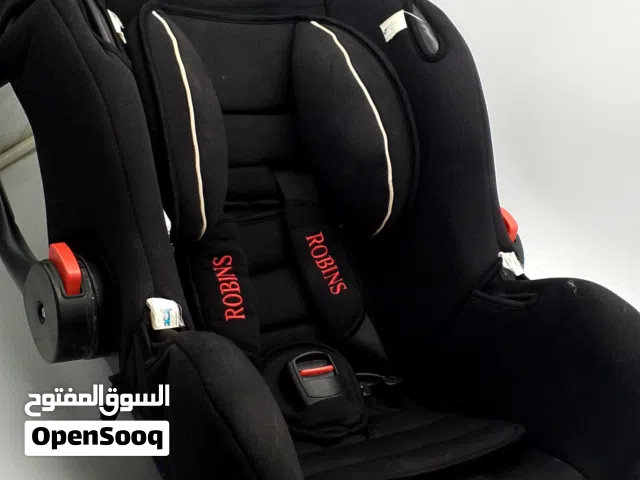مقعد السيارة أسود للأطفال ماركة روبنز ببطانة حمراء تحمل العلامة التجارية وحزام أمان