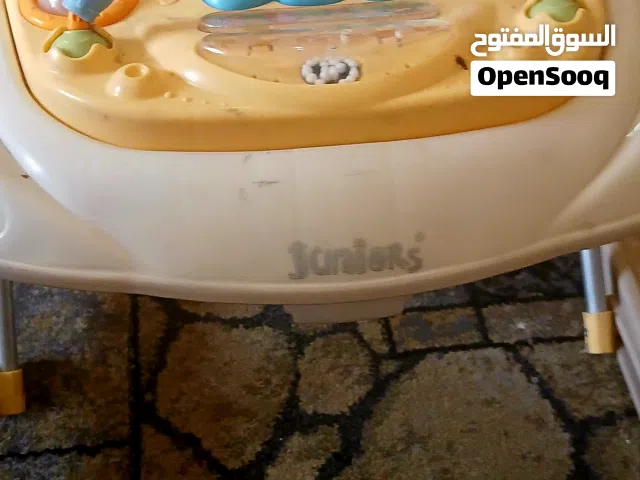 مشاية أطفال من ماركة جونيورز (Juniors) ذات لون أصفر ومقعد مبطن برسومات ملونة.  العلامة التجارية: جون