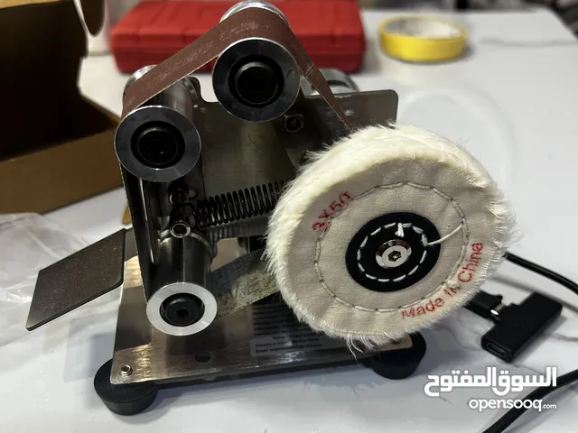 آلة صنفرة حزام كهربائية صغيرة، تُستخدم لشحذ وتلميع المواد المختلفة.