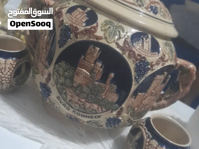 للبيع قطعة خزفية ألمانية قديمة مميزة مع غطاء وكأسين أصليين. تحمل رسومات بارزة لمعالم المانيه