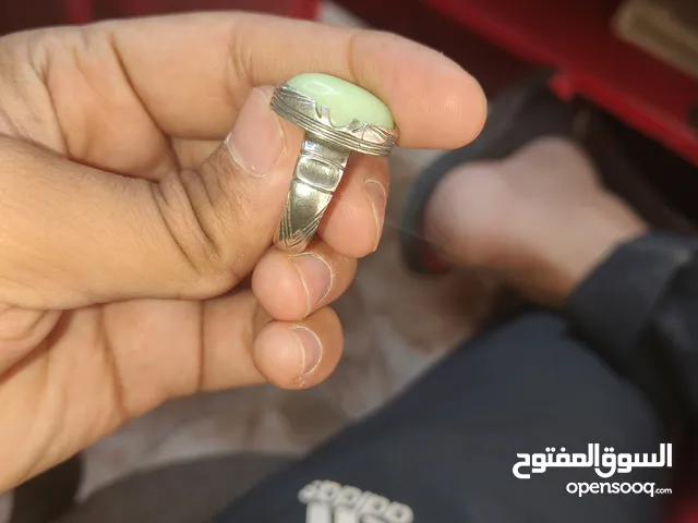 خاتم فضة بتصميم جميل جدًا، يتميز بحجر مركزي لونه أخضر فاتح ذو لمعة فسفورية، مما يجعله يبدو مضيئًا