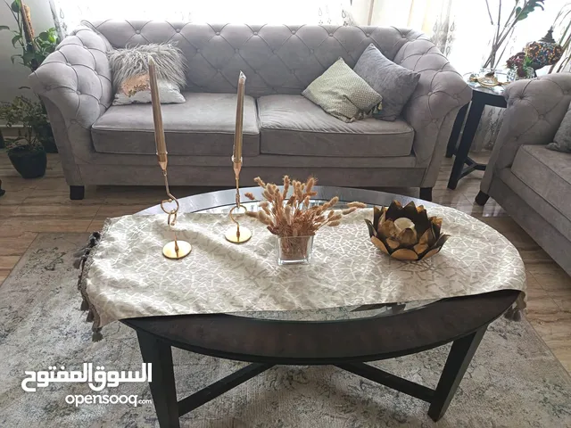 غرفة ضيوف بحالة جيدة مكونة من كنب وطاولة وسط