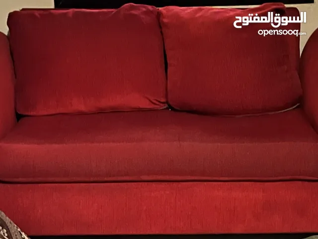 كنب احمر 7 مقاعد نظيف مع طاولة بيج خشبية كبيرة من ايكيا