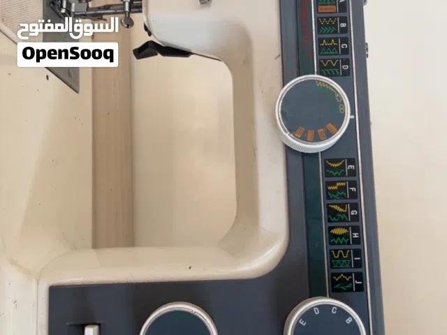 ماكينة خياطة جانومي طراز 393، وتتميز بهيكل معدني متين ولون أبيض مع تفاصيل رمادية./