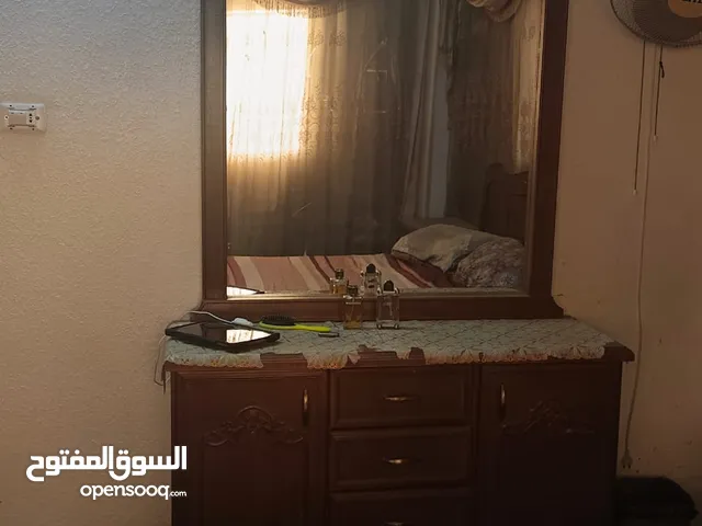 غرفة نوم مع سرير خزانة والستائر والمرأة جوارير بجانب السرير وشماعة