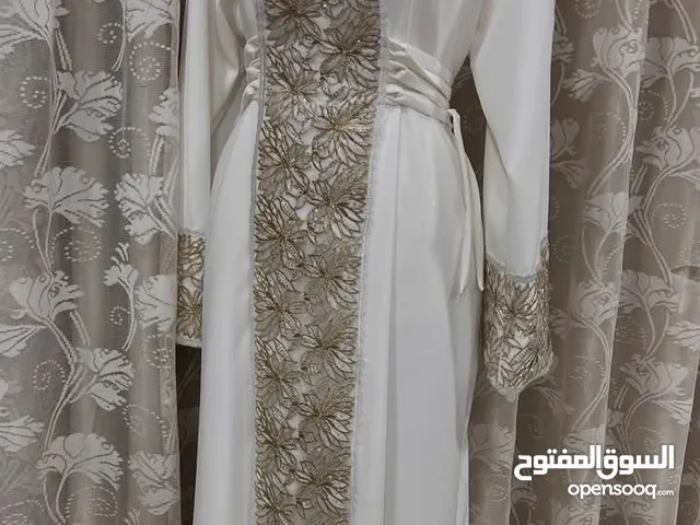 أناقة تليق بكِ فستان نسائي فاخر بلون أبيض ملكي ولمسات تطريز فخمة بالذهبي اللامع.