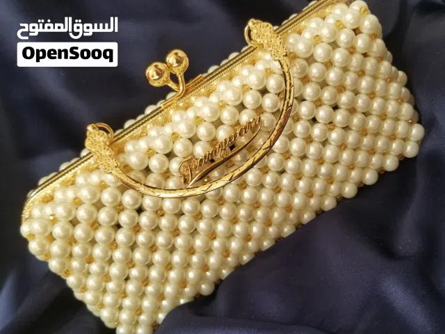 شنطة يد عبارة عن قطعة فنية فخمة بلون لؤلؤي ولمسات كريستالية فخمة متوفرة لدى لوكسيا للفن اليدوي