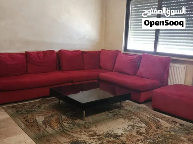 غرفة معيشة كنب كورنر احمر فاخر مع طاولة سوداء لامع