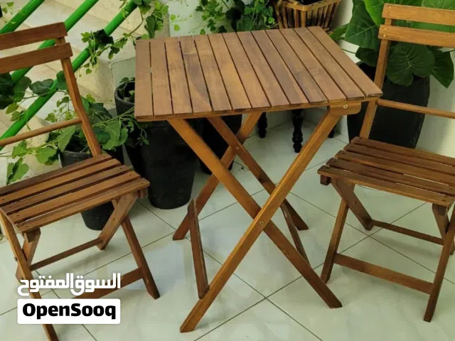 طاولة وكراسي قابلة للطي وسنادين ونباتات زينة