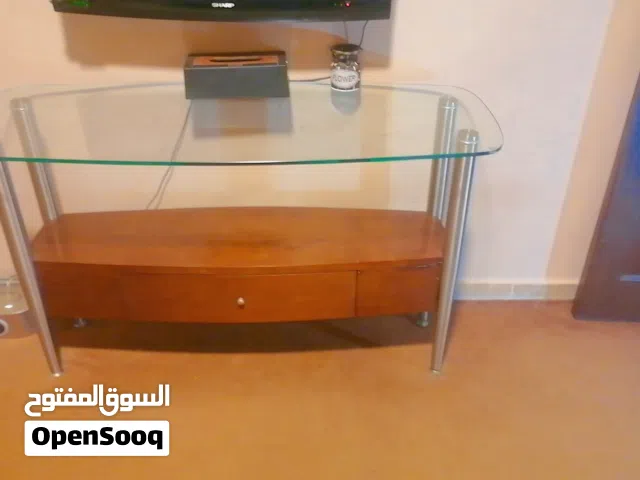 طاولة تلفزيون أو طاولة كونسول بتصميم عصري يجمع بين الخشب والزجاج والمعدن.