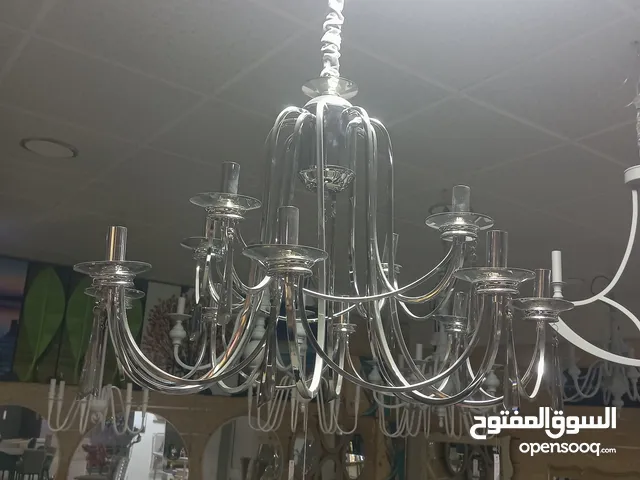 ثريا 12 لامبه في قلب معدنٍ مصقول، تنساب أذرعه بانسجام كأنها سيمفونية صامتة تعزف ألحان الضوء