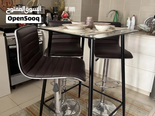 طاولة طعام زجاج مع ثلاث كراسي جلدية