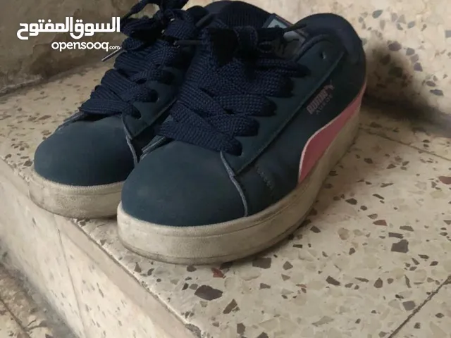 حذاء رياضي من طراز Puma Roma Suede باللون الأزرق الداكن والوردي.
